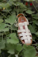 Sandalias de cuero marrón con tiras entrecruzadas y hebilla dorada al tobillo.