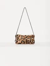 Mini cartera tipo baguette con estampado de leopardo, confeccionada en cuero y pelo vacuno. Tiene correa fina al hombro del mismo material y aplique metálico con el logo JCH en el frente.