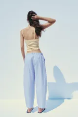 Pantalón tipo barrel con rayas verticales celestes y blancas, tiro medio y cintura elástica ajustable con lazo. Tiene bolsillos laterales y falsos bolsillos de vivo en la espalda.