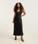 Vestido midi negro de satén con breteles finos y escote en V con detalle de encaje en el busto.