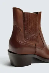 Bota de cuero color marrón, estilo cowboy, con caña corta, puntera en punta y tacón cubano.