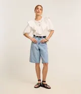 Blusa blanca de tricolina con cuello redondo, mangas cortas abullonadas y detalle de laise en el pecho.