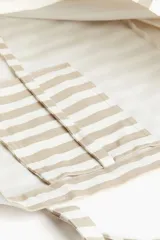 Bolso de playa tipo tote bag, de lona de algodón a rayas horizontales color beige y blanco. Tiene doble asa de hombro y un compartimento interior.