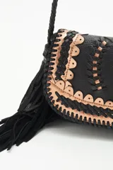 Cartera bandolera negra de cuero con diseño trenzado en el frente y flecos en gamuza. Tiene correa trenzada con terminación y forro de algodón.