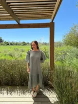 Vestido largo color beige, de corte amplio, con mangas cortas abullonadas y volado en el ruedo.