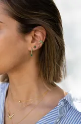 Aros dorados tipo argolla con incrustaciones de circonitas verdes y dije colgante de circonita verde en forma de lágrima.