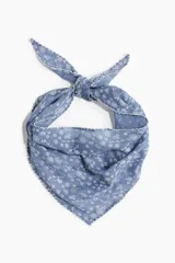 Pañuelo triangular de tela celeste con estampado de flores blancas y borde festoneado. Se ata en la nuca.