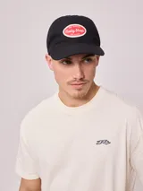 Gorra de lona lavada color azul con visera curva y parche bordado con el logo de Rusty en el frente.