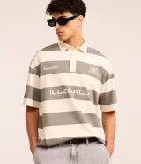 Camisa polo oversized con cuello abotonado, mangas cortas y diseño a rayas horizontales en tonos crema y gris. Presenta estampados con texto en el pecho.