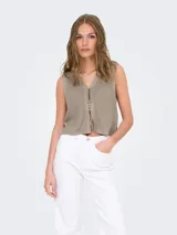 Chaleco de punto color beige, sin mangas, con cuello en V y cierre frontal con lazos.