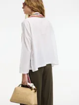Camisa beige de algodón con botones frontales y cuello camisero.