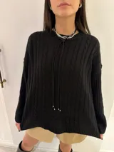 Sweater tejido color salmón, con cuello redondo y diseño de ochos en el frente y rayas en las mangas.