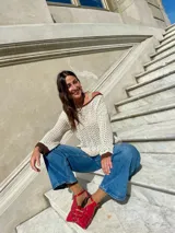 Sweater de punto calado color crema, con cuello, puños y ruedo en marrón con lurex. El cuello puede usarse de dos formas: mostrando un hombro o de forma clásica.