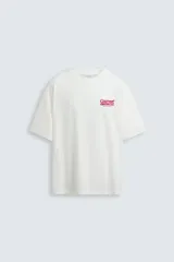 Camiseta blanca de corte holgado, cuello redondo y manga corta. Estampado frontal con la frase "Gourmet Groove LLC" en color fucsia.