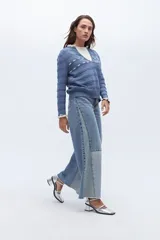 Sweater de punto negro con detalle de calados y lazo en el escote. Tiene ribetes con volados en contraste en el cuello y puños.