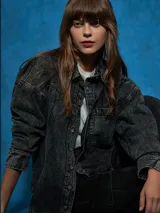 Sobrecamisa negra de denim con cuello clásico, cierre frontal con botones a presión, mangas largas con puños abotonados, dos bolsillos con solapa en el pecho y corte holgado.