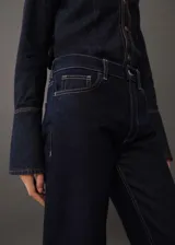 Pantalón de jean azul oscuro, de corte recto, con tiro alto, cinco bolsillos y cierre de cremallera y botón.