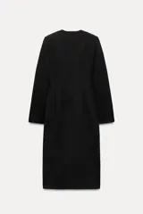 Vestido midi negro de escote pico y manga larga con hombreras. Tiene falsos bolsillos de vivo en el delantero y cierre en la espalda con cremallera oculta.