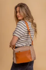 Bandolera de diseño moderno, color beige rosado, con correa regulable y bolsillo frontal con cierre.