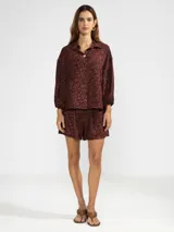 Camisa de manga 3/4 con puños elastizados, cuello camisero y estampado de figuras humanas y peces en color crema sobre fondo negro.