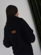 Campera corta negra con cuello y puños de piel sintética negra. Cierre con presillas de madera.