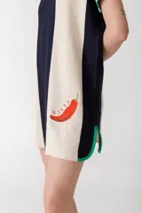 Vestido corto tejido en jersey liviano de algodón y acrílico, con diseño tipo polo y fit holgado. Presenta rayas verticales en color marrón y crudo, bordado XL de un ají y terminaciones en color amarillo.