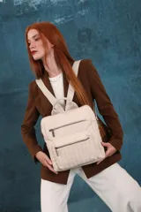 Mochila mediana de símil cuero color beige, con asa superior, dos compartimentos principales con cierre y dos bolsillos frontales con cierre. Las correas son ajustables y de color beige.