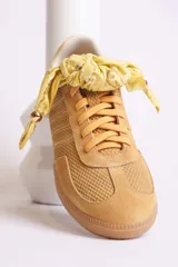 Zapatillas bajas de gamuza celeste con cordones y pañuelos estampados atados a los cordones.