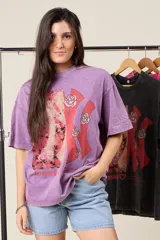 Remera oversize color lila con estampado de una letra K roja con rosas y un diseño abstracto.
