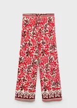 Pantalón de viscosa con estampado floral en tonos rojo, blanco y marrón. Tiene cintura elástica con cordón ajustable, corte recto y dos bolsillos laterales.