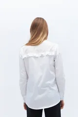 Camisa blanca de algodón con bordado calado, cuello alto con volados y cierre frontal con botones.