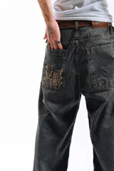 Pantalón de jean azul desgastado, corte mega baggy, con bordado dorado en el bolsillo trasero y botones personalizados.