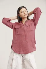 Camisa de lino color beige con cuello clásico, cierre frontal con botones, mangas largas con trabillas para enrollar y dos bolsillos con solapa en el pecho.