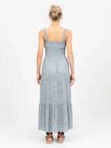 Vestido largo de lino azul claro con estampado de finas rayas verticales en color salmón. El corpiño es fruncido (smock) y el vestido tiene falda escalonada con volados.