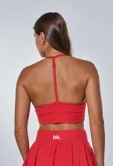 Conjunto deportivo rojo compuesto por un top con tirantes finos cruzados en la espalda y una minifalda tableada.