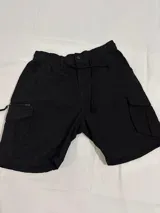 Bermuda negra estilo cargo con corte holgado, bolsillos laterales con cierre y cintura elástica.