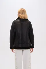 Campera negra de eco cuero con cuello de piel sintética, cierre cruzado con cremallera y bolsillos laterales con cremallera.