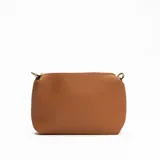 Cartera tipo hobo de cuero sintético color crema con laterales y asa corta color marrón.