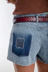 Cinturón de cuero color bordó con costura de tientos en color azul oscuro a lo largo de los bordes. Posee hebilla metálica rectangular plateada.