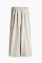 Pantalón de vestir color beige, de corte ancho y tiro alto, con pinzas delanteras, bolsillos laterales y cierre frontal.