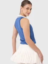 Top deportivo blanco con cuello polo y ribete verde oscuro.
