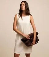Vestido corto color crudo, confeccionado en viscolino, con escote redondo, breteles anchos y cierre en la espalda.