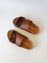 Sandalias bajas de cuero marrón con estampado animal print en las tiras.