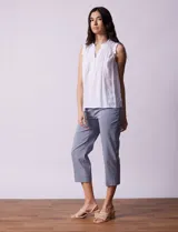 Blusa blanca de gasa marca Zac & Rachel, sin mangas, con cuello a la base con frunce, escote en V con botones, delantera plisada y apliques en crochet.
