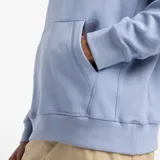 Canguro celeste de corte holgado con capucha y bolsillo tipo canguro. Logo de New Balance bordado en el pecho.