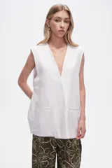 Chaleco largo sin mangas color blanco, con cuello en V y bolsillos frontales.