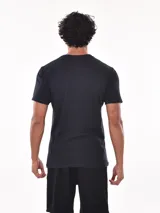 Remera negra de corte oversized con bolsillo en el pecho y detalle de bloque gris en el lateral.