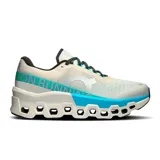 Championes de running On Running Cloudmonster 2, color crema con detalles en turquesa y verde. Presentan el logo de la marca en el lateral y suela con tecnología CloudTec.