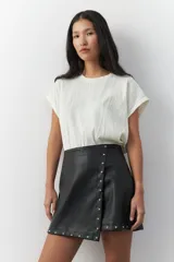 Short tipo pollera en símil cuero negro, con apliques de tachas en la parte frontal.