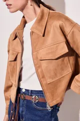 Campera de gamuza en color tostado, con corte ajustado y cierre frontal.